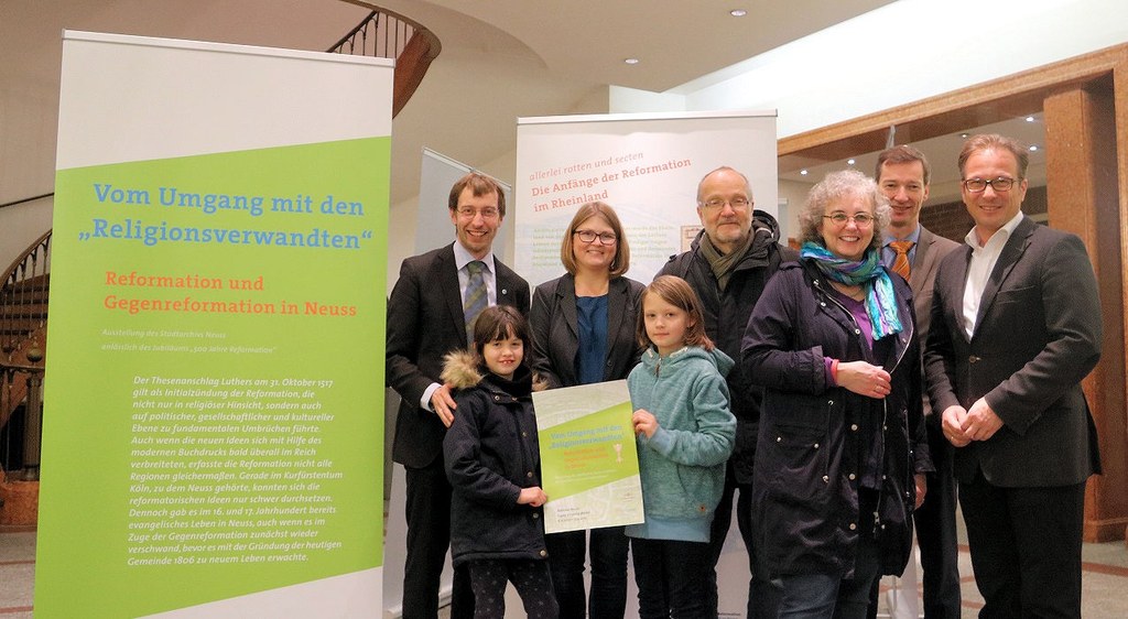 Pfarrer Sebastian Appelfeller, Verbandsvorsitzender der evangelischen Kirchengemeinden in Neuss, Historikerin Dr. Stefanie Fraedrich-Nowag, Dr. Jens Metzdorf, Leiter des Neusser Stadtarchivs, und Bürgermeister Reiner Breuer vor der Wanderausstellung.