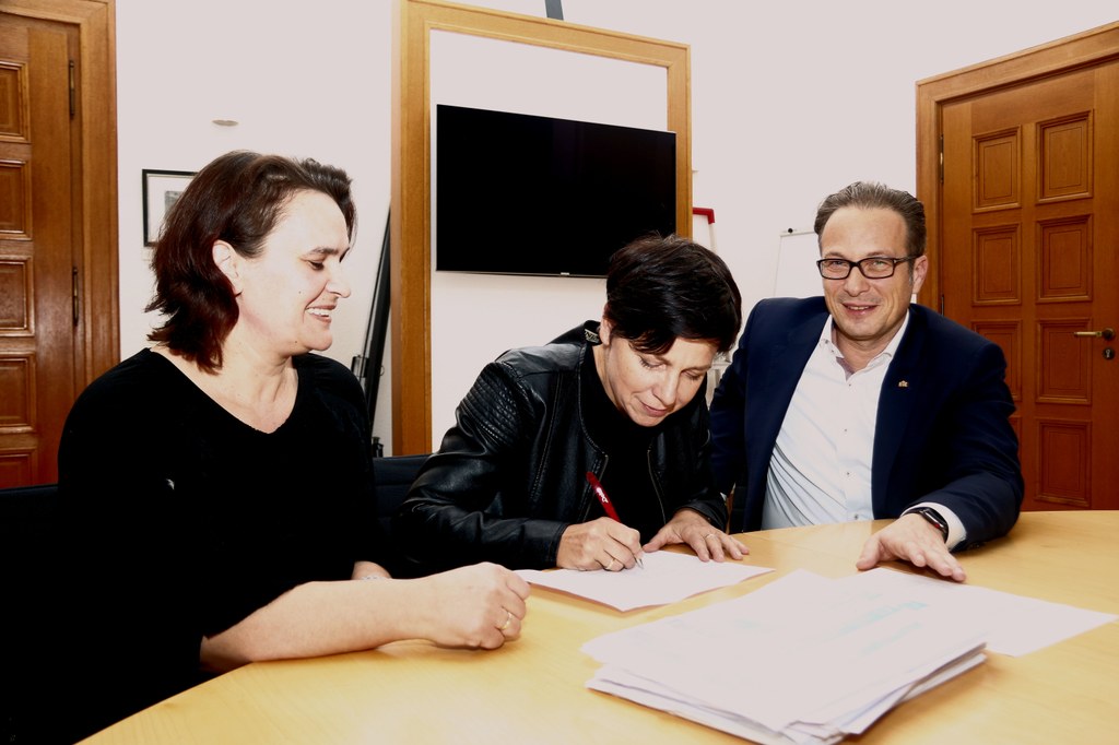 Silke Welter, Schulpflegschaftsvorsitzende der Comenius-Schule, leistet im Beisein von Bürgermeister Reiner Breuer und Mit-Initiatorin Atidza Fazlija die letzte Unterschrift für das Bürgerbegehren „Für mehr Gesamtschulplätze“.